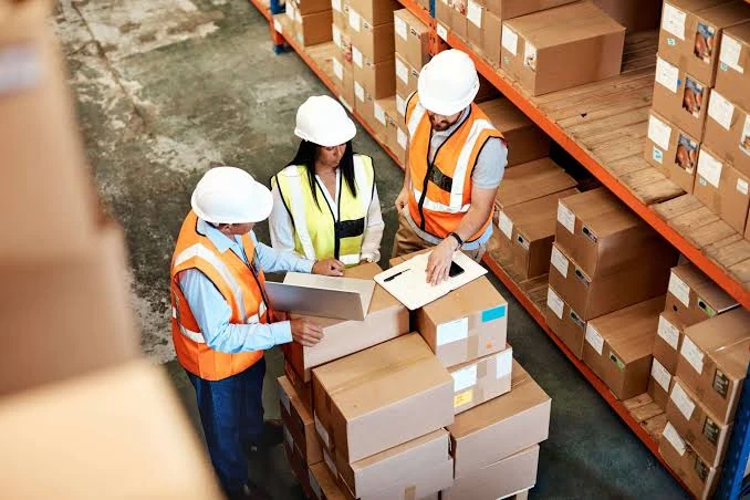 Equipe de supervisão conferindo caixas no galpão